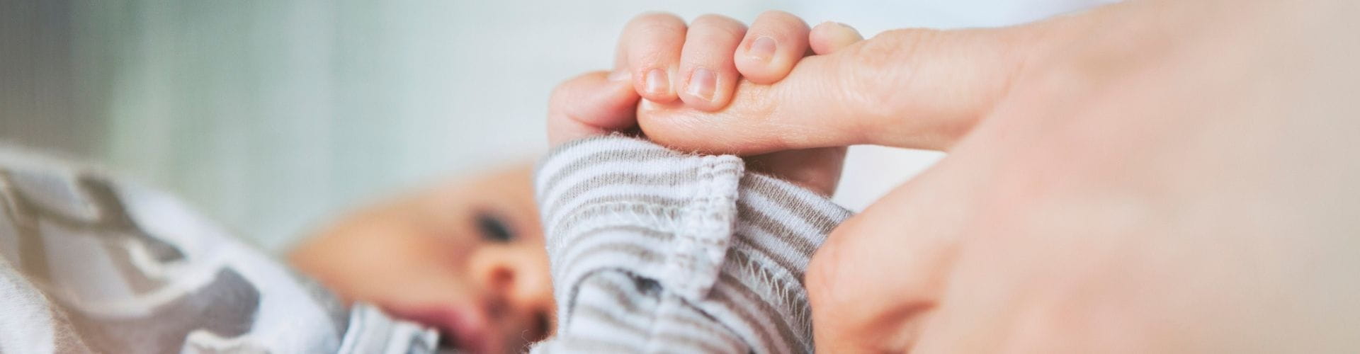Newborn baby holds mom's finger