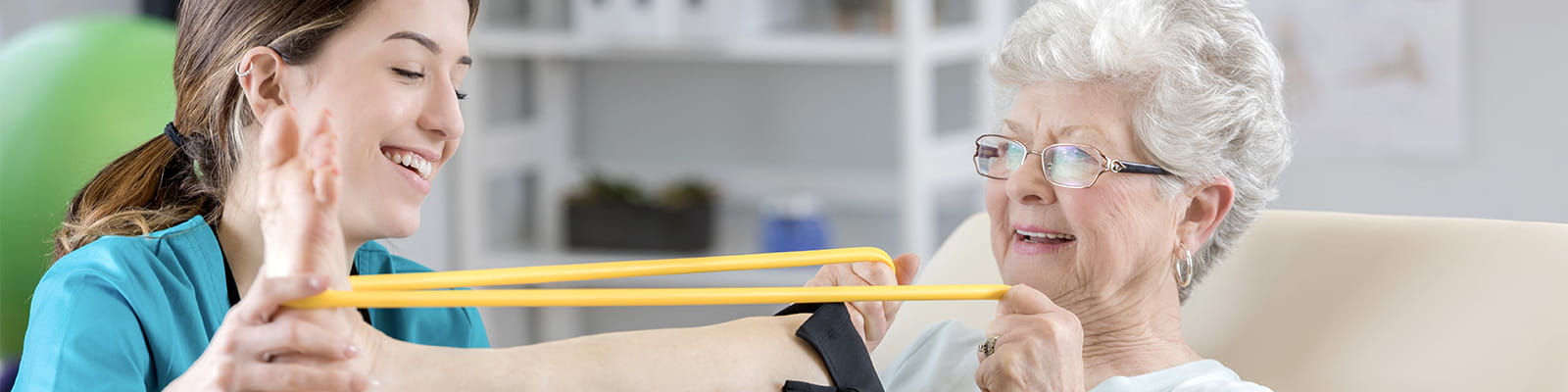 Young physical therapist helping an eldery female patient