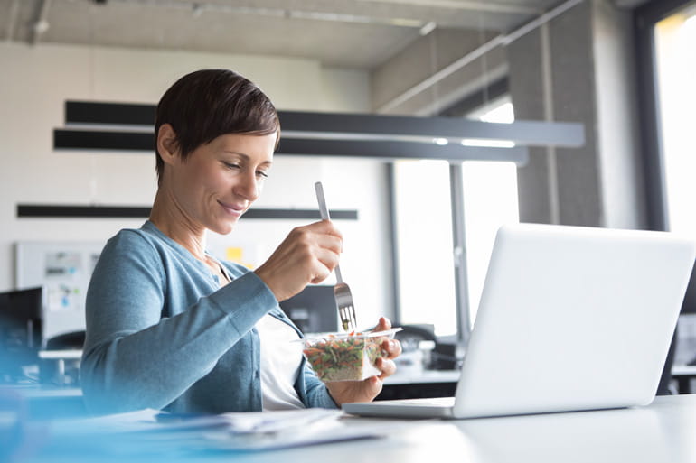 Woman at office eating healthy lunch during break